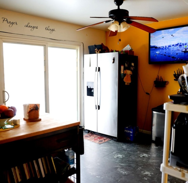 kitchen with concrete flooring, white refrigerator with ice dispenser, wood counters, and a ceiling fan