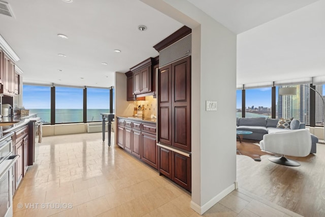 kitchen featuring open floor plan, a water view, a wealth of natural light, and baseboards