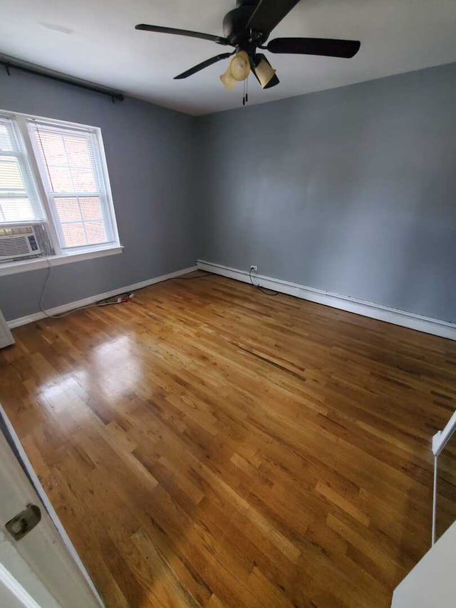 unfurnished room featuring a ceiling fan, baseboards, cooling unit, and wood finished floors