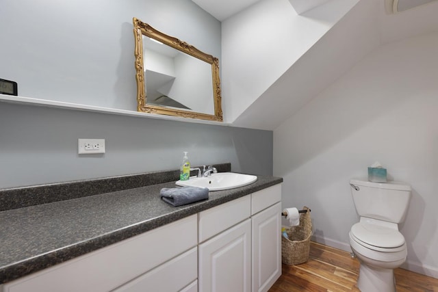 half bathroom featuring baseboards, vanity, toilet, and wood finished floors