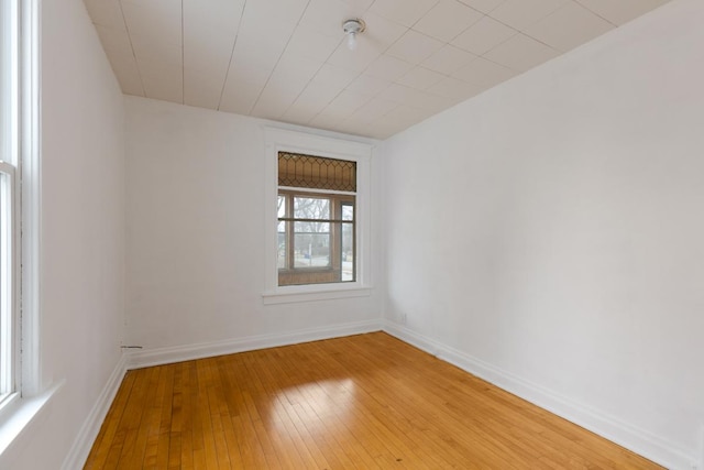 spare room with baseboards and light wood-style floors