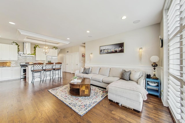 living area with a chandelier, recessed lighting, a raised ceiling, and dark wood finished floors