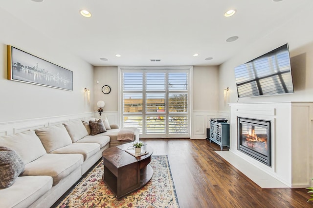 living area featuring recessed lighting, a fireplace with flush hearth, wood finished floors, and wainscoting