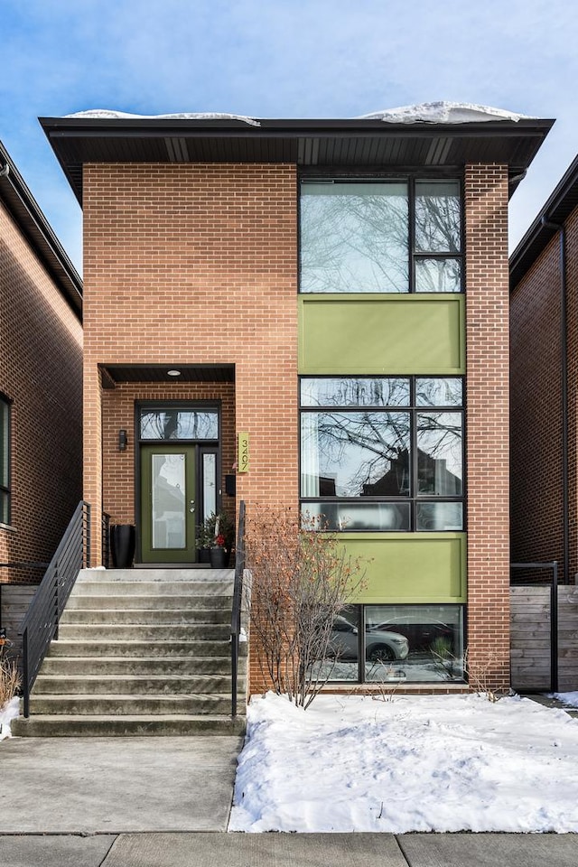 snow covered property entrance with brick siding