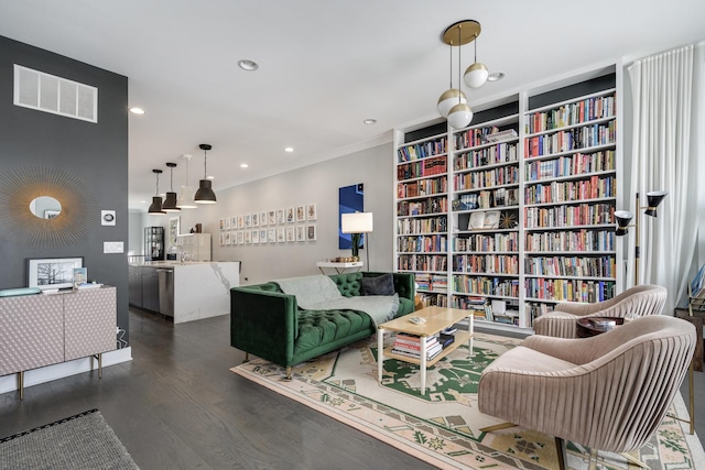 living room featuring dark wood-style floors, recessed lighting, visible vents, bookshelves, and ornamental molding