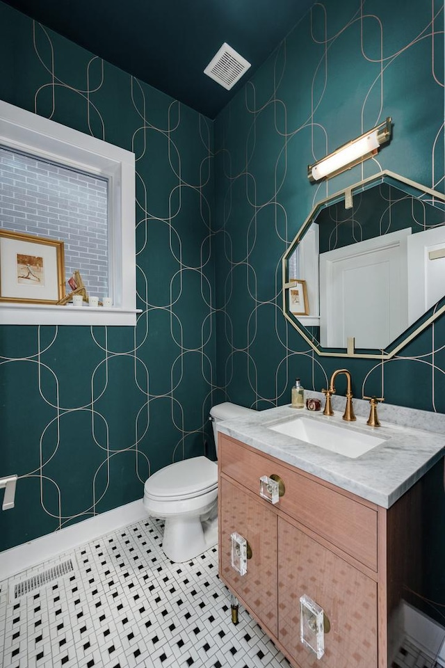 half bath featuring toilet, vanity, visible vents, and tile patterned floors