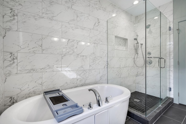 bathroom with a stall shower, a tub, and tile patterned floors