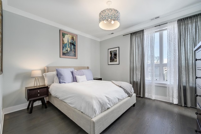 bedroom with ornamental molding, dark wood-type flooring, visible vents, and baseboards