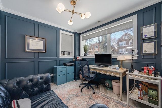 office featuring a notable chandelier, a decorative wall, visible vents, ornamental molding, and light wood-type flooring