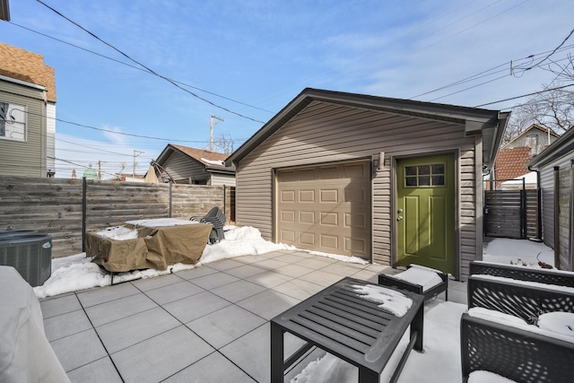 exterior space featuring an outbuilding, central air condition unit, a detached garage, fence, and concrete driveway