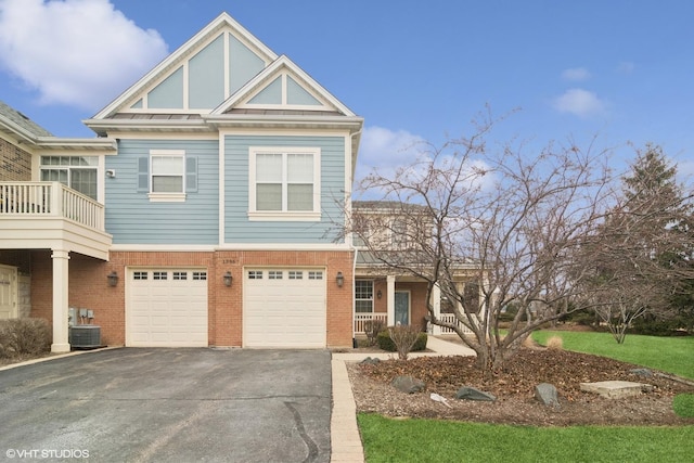 view of front of property featuring driveway, a garage, covered porch, central AC, and brick siding