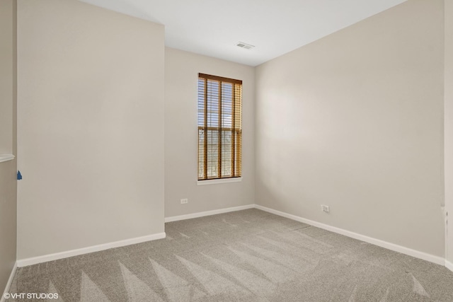 carpeted spare room featuring visible vents and baseboards