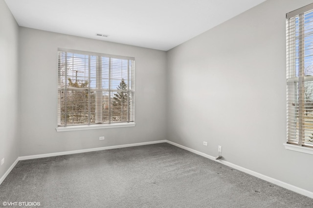 carpeted empty room with visible vents, plenty of natural light, and baseboards