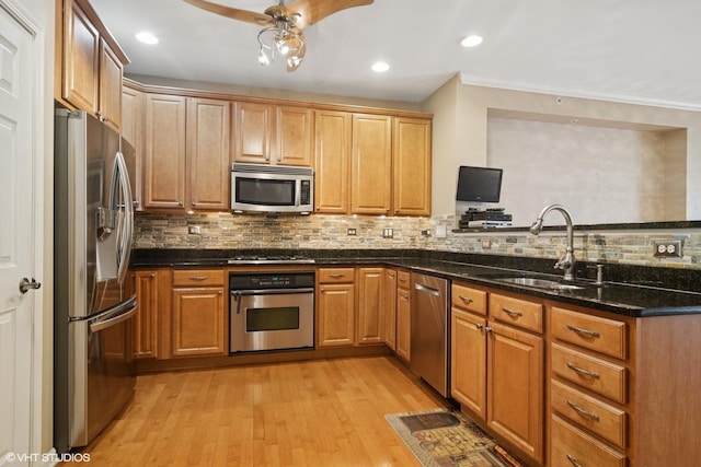 kitchen with light wood-style flooring, appliances with stainless steel finishes, tasteful backsplash, and a sink