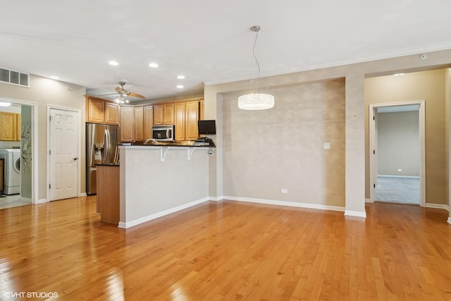 kitchen with stainless steel appliances, a peninsula, visible vents, light wood-style floors, and dark countertops