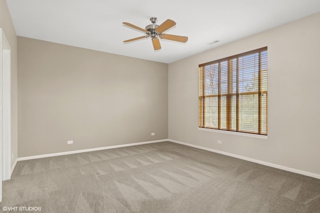 carpeted spare room featuring baseboards, visible vents, and a ceiling fan