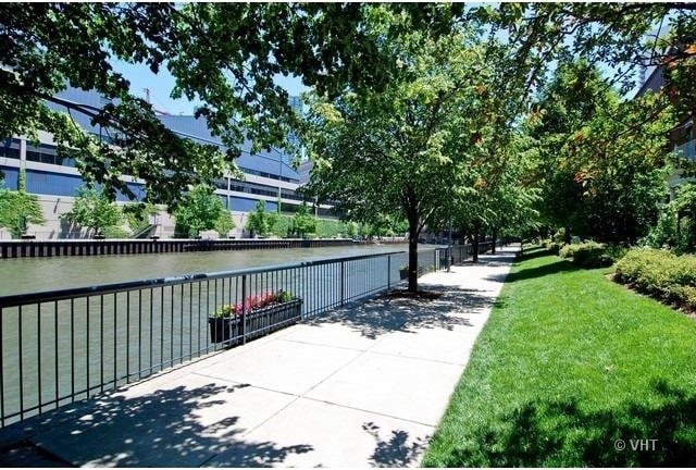 view of home's community with a water view, fence, and a lawn