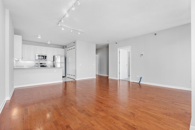 unfurnished living room with rail lighting, baseboards, and light wood finished floors