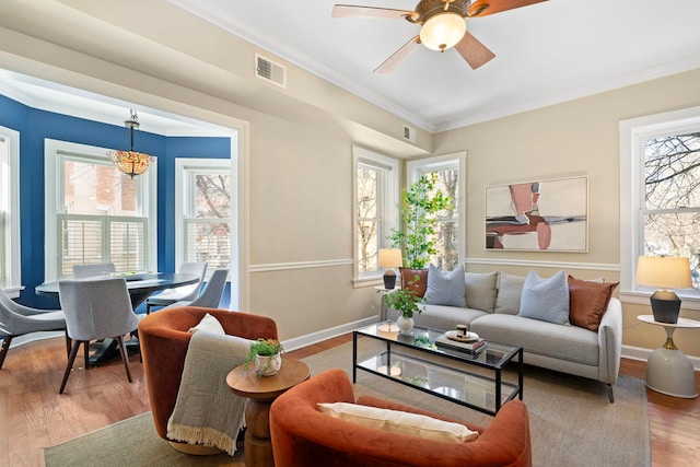 living room with a wealth of natural light, visible vents, and wood finished floors