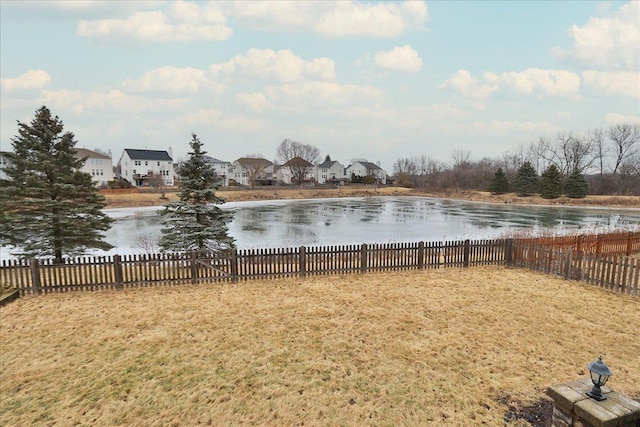 view of yard featuring a residential view, a fenced backyard, and a water view