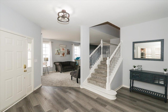 foyer entrance with stairway, wood finished floors, and baseboards