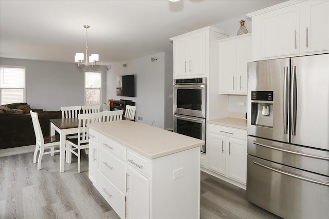 kitchen with white cabinets, open floor plan, wood finished floors, a center island, and stainless steel appliances