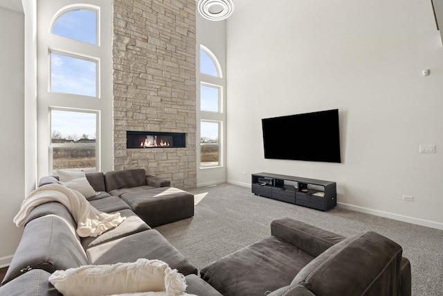 carpeted living area with a high ceiling, a fireplace, and baseboards