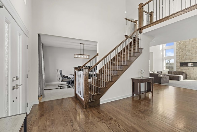 entrance foyer featuring stairs, dark wood finished floors, a towering ceiling, and baseboards