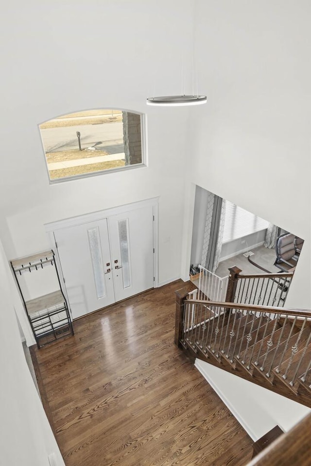 entryway featuring dark wood-style floors, stairway, and a high ceiling