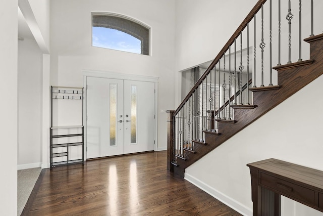 foyer featuring dark wood-type flooring, a high ceiling, baseboards, stairs, and french doors