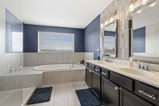 bathroom with double vanity, a bath, a sink, and tile patterned floors