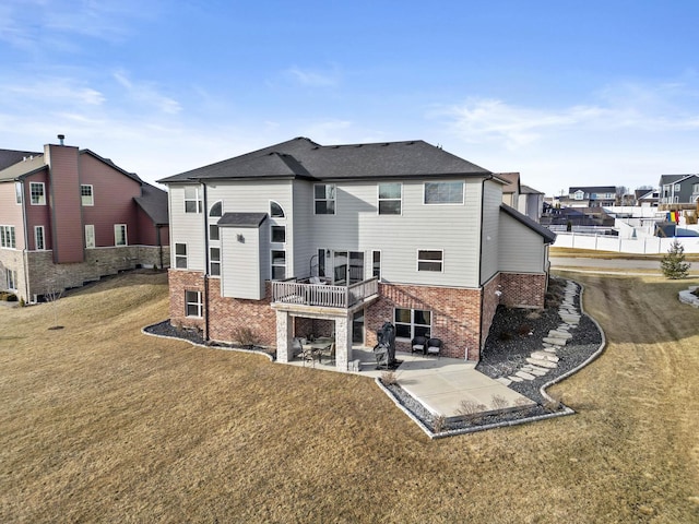 back of property featuring a yard, a residential view, brick siding, and a patio