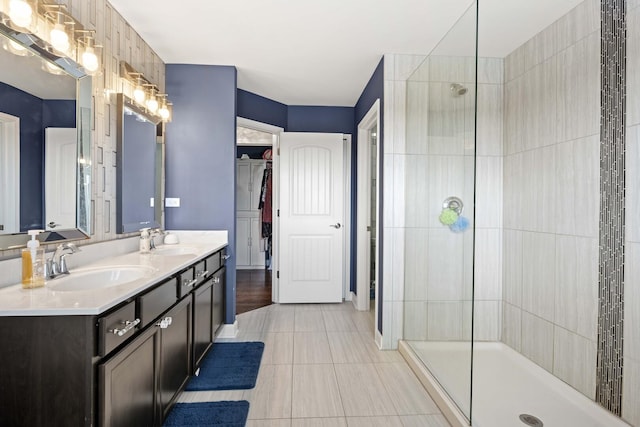 full bath featuring double vanity, a walk in shower, a sink, and tile patterned floors