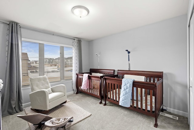 carpeted bedroom with a nursery area, visible vents, and baseboards