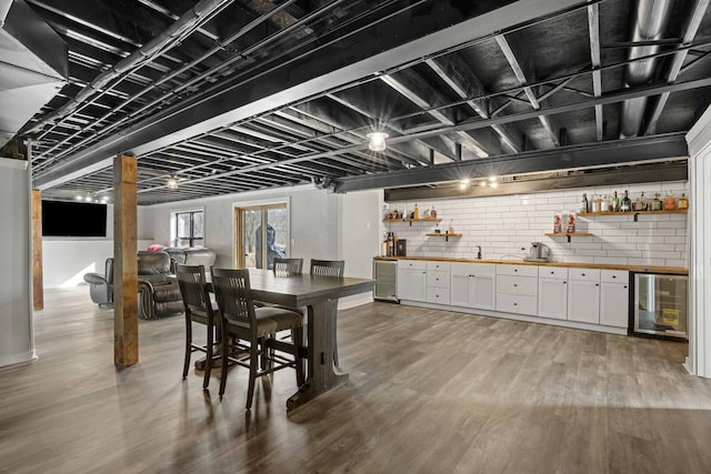 dining space with wine cooler, indoor wet bar, and wood finished floors