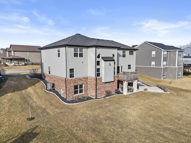 back of property with a residential view, brick siding, and a lawn