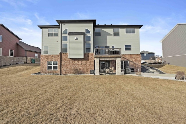 rear view of house featuring a yard, brick siding, and a balcony