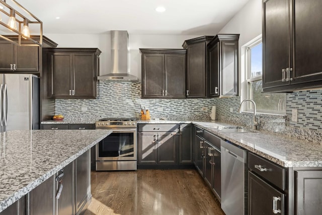 kitchen with stainless steel appliances, dark wood-style flooring, a sink, backsplash, and wall chimney exhaust hood