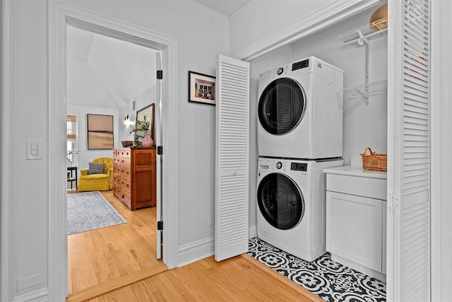 washroom with stacked washer / dryer, light wood-type flooring, and cabinet space