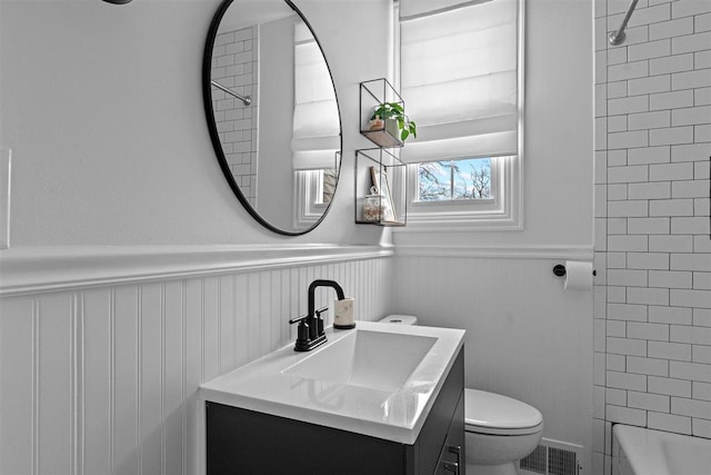 full bath with visible vents, wainscoting, toilet, vanity, and shower / washtub combination