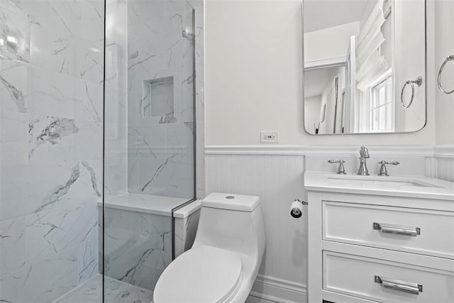 bathroom with a marble finish shower, wainscoting, vanity, and toilet