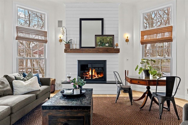 living room featuring a large fireplace, a healthy amount of sunlight, and wood finished floors