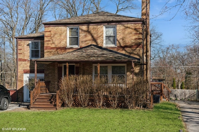 view of front of house featuring brick siding, stairway, a porch, a front yard, and roof with shingles