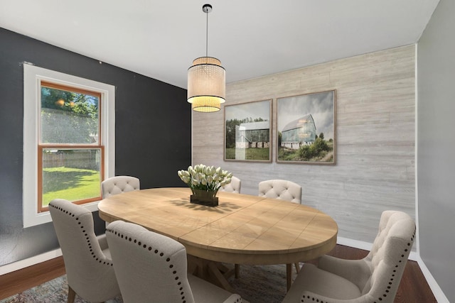 dining room with an accent wall, wood finished floors, and baseboards