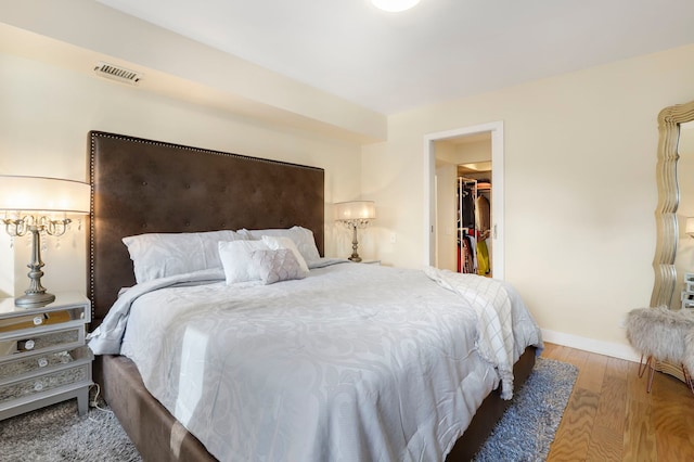 bedroom featuring light wood-style flooring, visible vents, baseboards, a closet, and a walk in closet