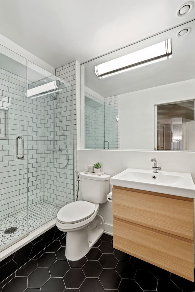 bathroom featuring toilet, a stall shower, tile patterned flooring, and vanity