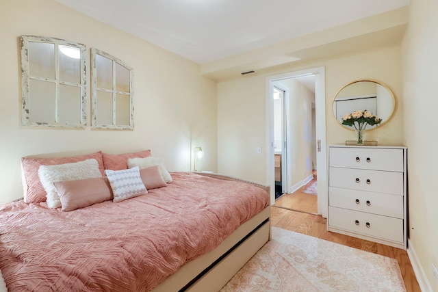 bedroom featuring light wood-style flooring, visible vents, and baseboards