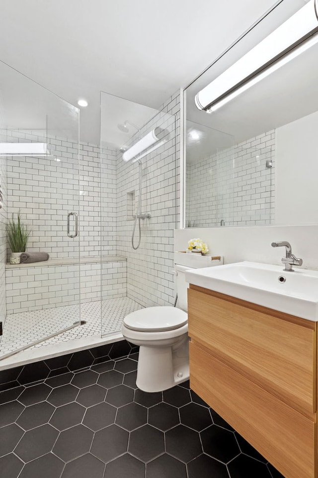 bathroom featuring toilet, tile walls, vanity, a shower stall, and tile patterned floors