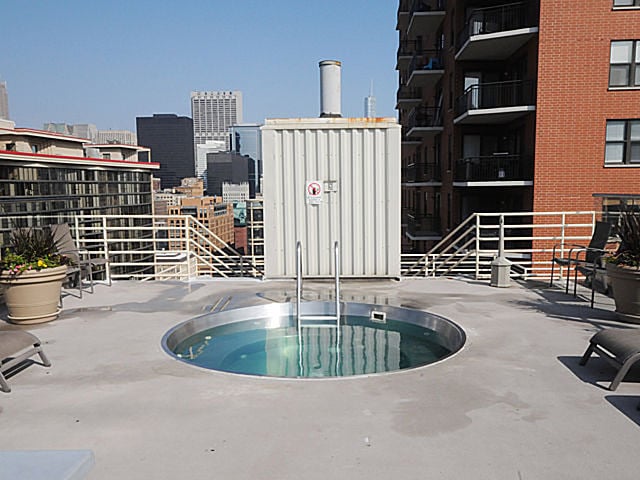 view of swimming pool with a patio area, a community hot tub, and a city view