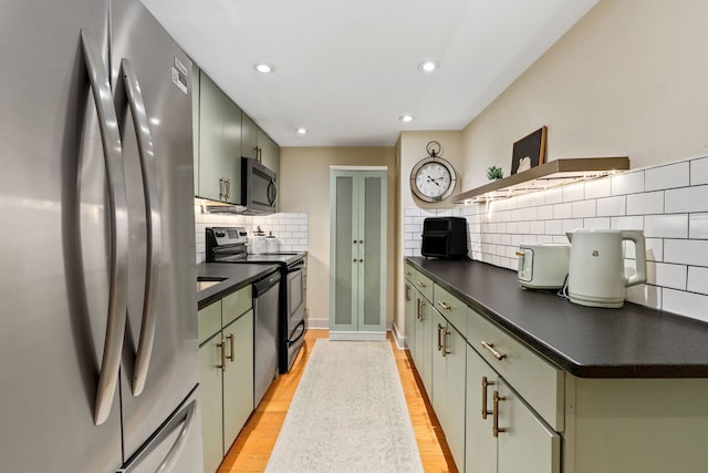 kitchen featuring stainless steel appliances, dark countertops, recessed lighting, light wood-type flooring, and green cabinetry